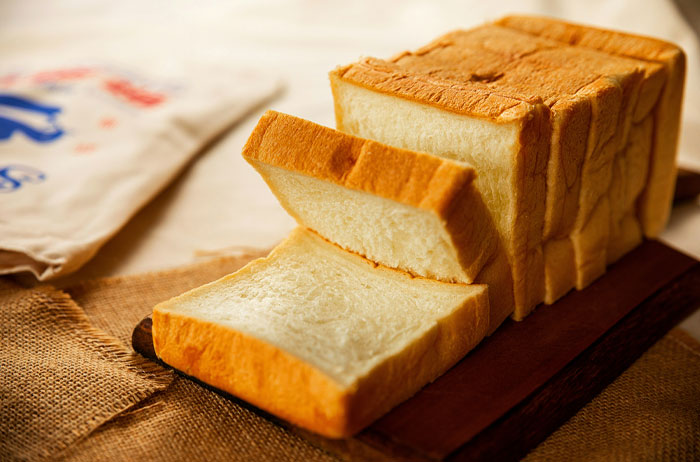 Sliced white bread loaf on a wooden board, representing American foods banned in other countries for health reasons.