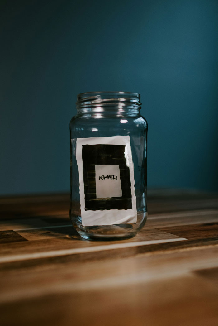 Glass jar on wooden surface containing a photo labeled memories, symbolizing psychological clues in dreams about people.