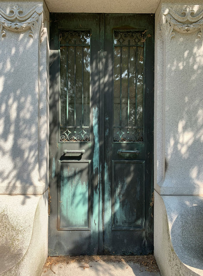 Old dark metal door with ornate details casting shadows, symbolizing psychological clues hidden in dreams about people.