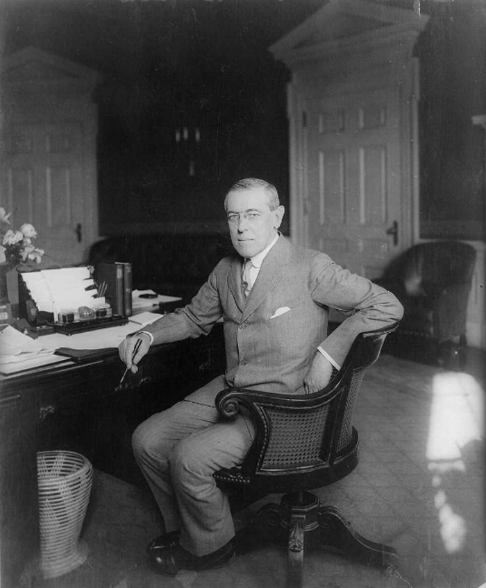 Black and white photo of US president Woodrow Wilson sitting at a desk, illustrating highest IQ among presidents concept.