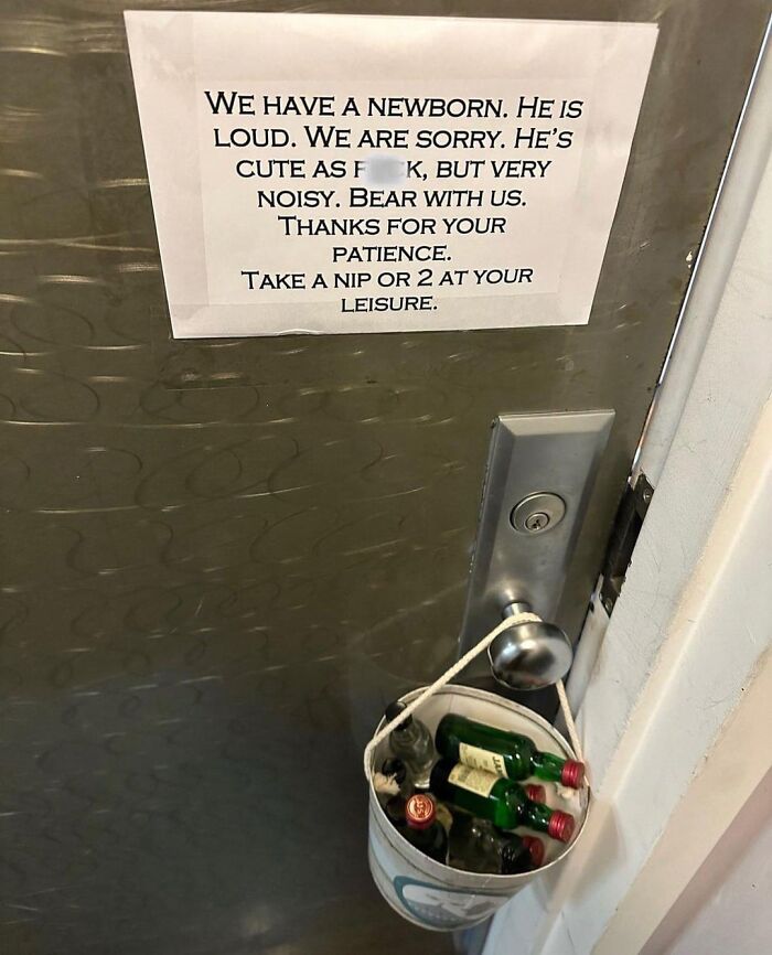Sign on a door apologizing for a noisy newborn with a bucket of alcohol bottles offered, showing wholesome people kindness.