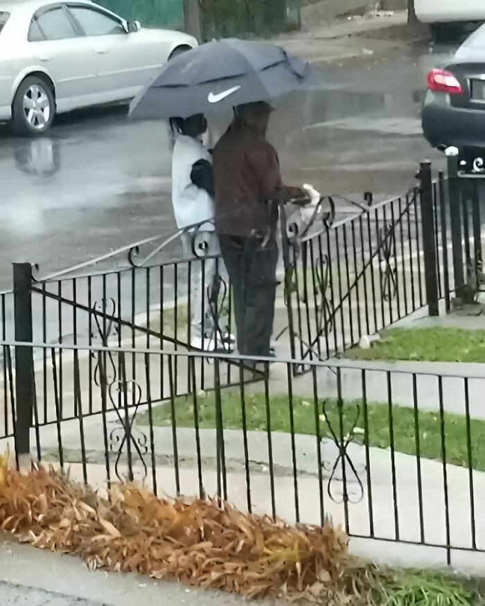 Two people sharing an umbrella on a rainy day, showing wholesome kindness that makes the world a better place.