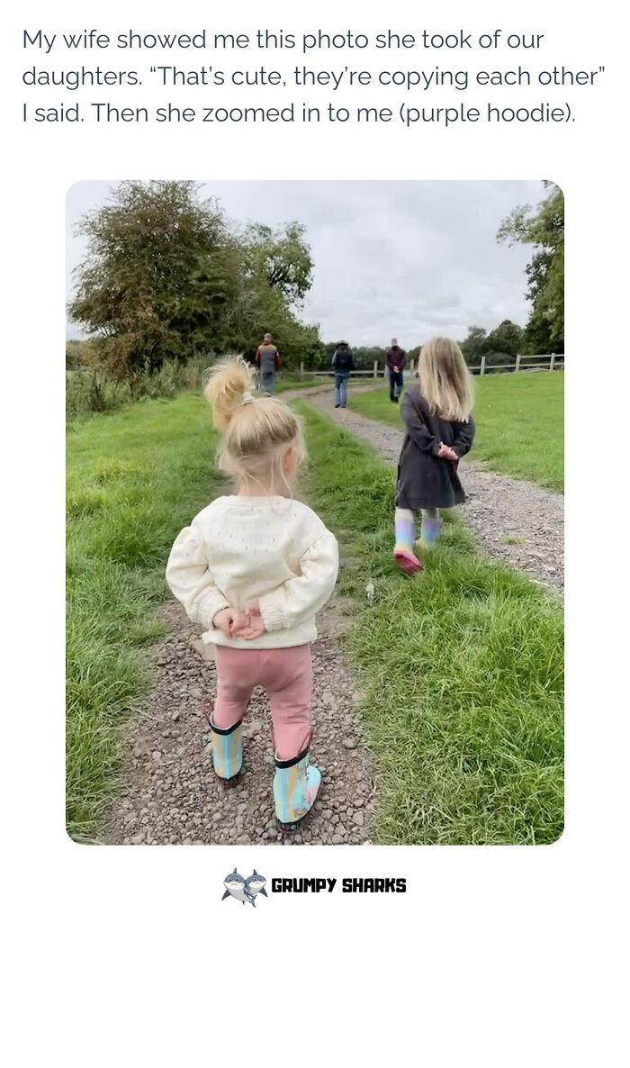 Two young children walking on a gravel path with hands behind their backs, a wholesome moment among people outdoors.