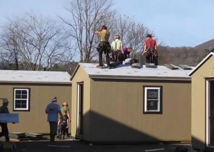 Group of Amish builders constructing tiny homes outdoors, showcasing wholesome and amazing community teamwork.
