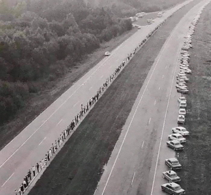 People forming a long human chain along a highway in a heartwarming display of unity and kindness in the wonderful world.