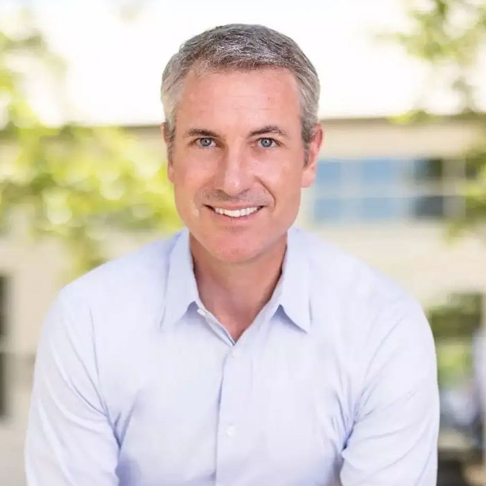 Portrait of a smiling CEO Andy Byron in a light shirt, related to Coldplay kiss cam cheating controversy.
