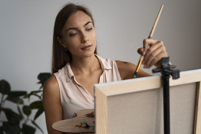 Young woman focused on painting a canvas indoors, reflecting on giving up life to follow partner tied to his mother. - 6