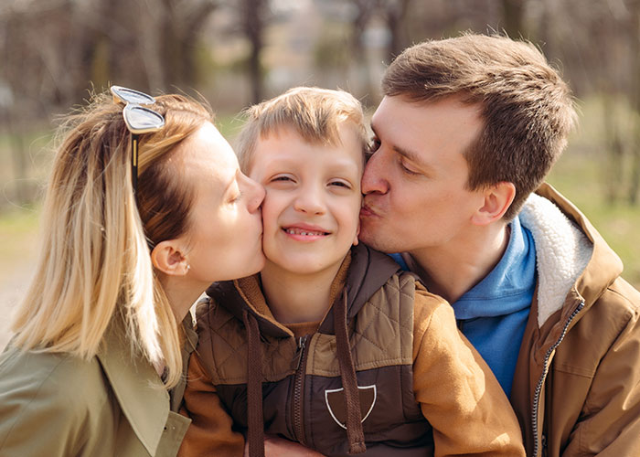 Co-parents showing affection to their child outdoors, highlighting challenges of misunderstandings and CPS involvement.
