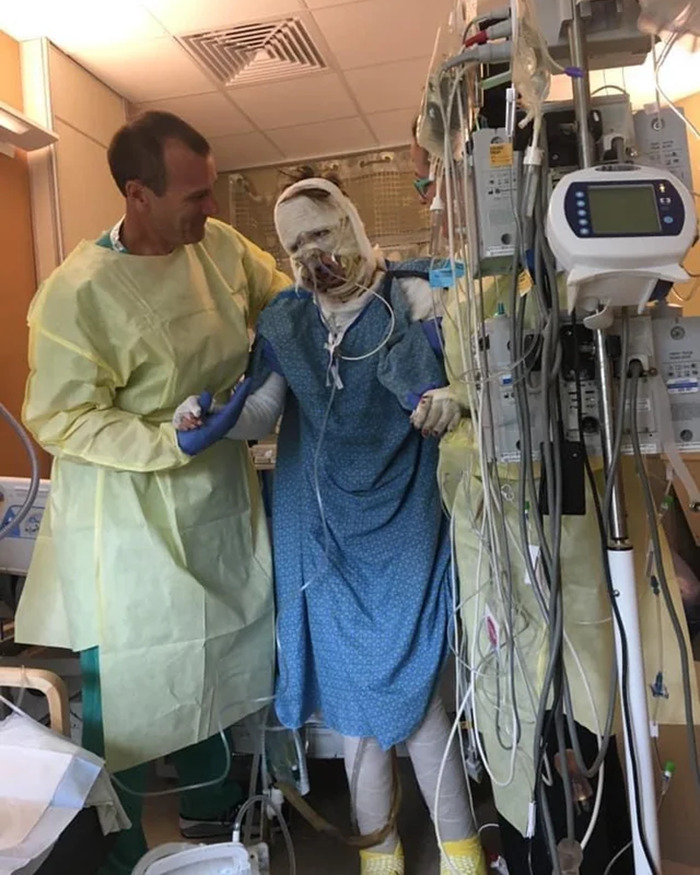 Woman burned in gas station explosion receiving medical care in hospital, connected to multiple IV and monitoring devices. - 2