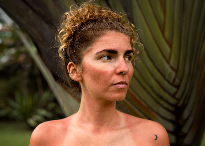 Young woman with natural look and curly hair outdoors, reflecting on facelifts and their impact on women at 28. Young woman with natural look and curly hair outdoors, reflecting on facelifts and their impact on women at 28.