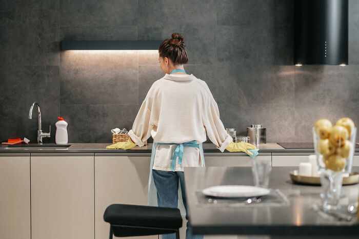 Woman wearing gloves cleaning a modern kitchen, illustrating things non-Americans do that make no sense to Americans. - 4