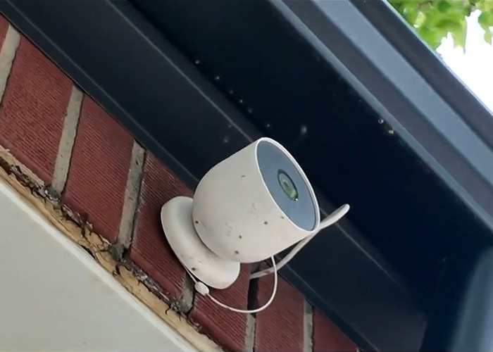 Security camera mounted on a brick wall near roofline, related to woman discovering phone buried in yard trend warning. Security camera mounted on a brick wall near roofline, related to woman discovering phone buried in yard trend warning.