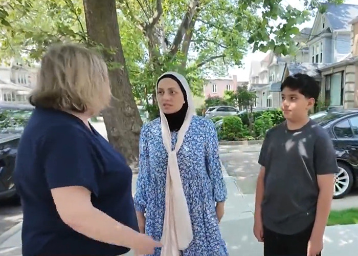 Woman wearing hijab and child talking with another woman outside in a yard amid police warning phone buried trend. Woman wearing hijab and child talking with another woman outside in a yard amid police warning phone buried trend.