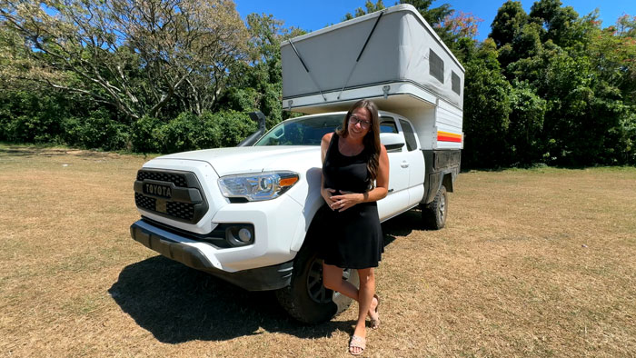 Woman in black dress standing next to white Toyota van, representing traveling the world in her van lifestyle. - 3
