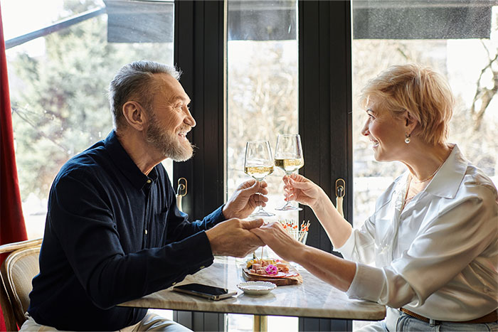 Couple toasting with wine glasses at a restaurant, illustrating servers witnessing the worst dates at work.