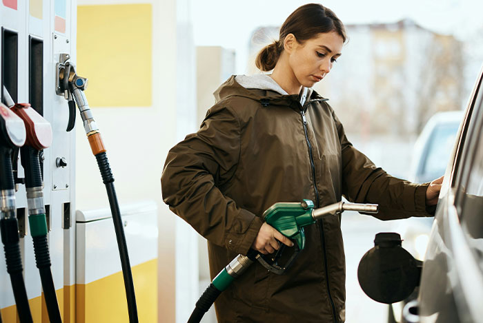 Woman at gas station pumping fuel into her car, captured in a candid moment reflecting mansplain reactions.
