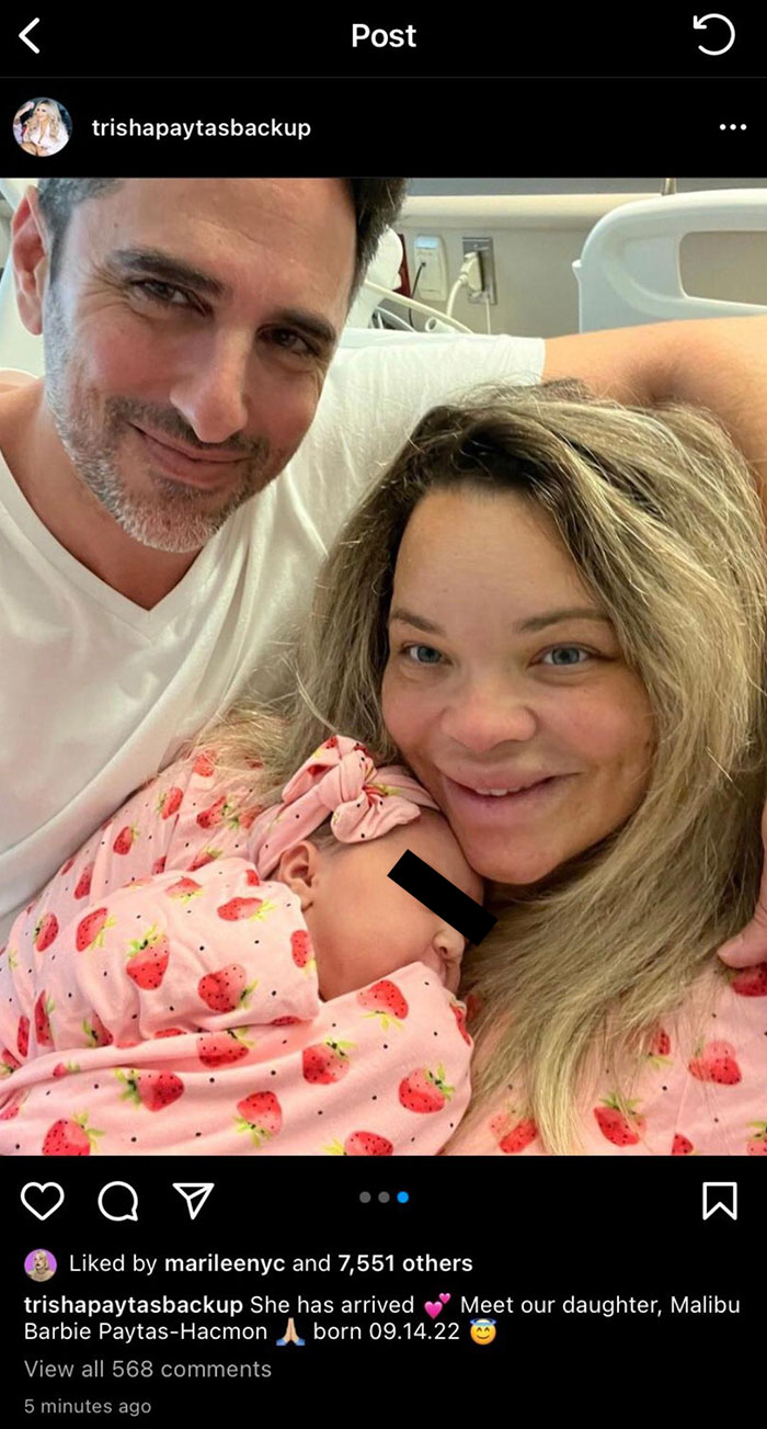 New parents smiling with their newborn baby wrapped in a pink strawberry outfit, highlighting unique baby names.