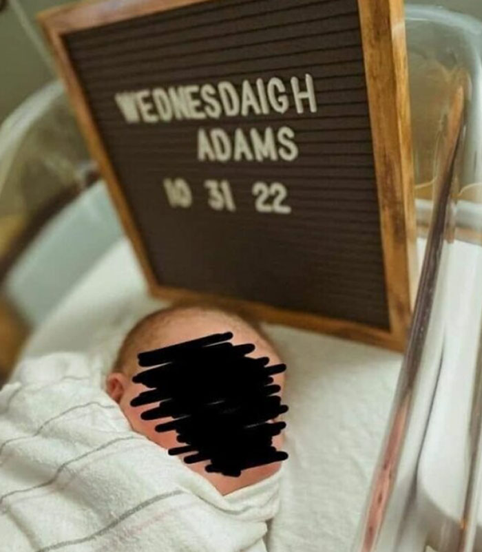 Newborn baby wrapped in a blanket beside a letter board with Wednesdaigh Adams baby name and birth date.