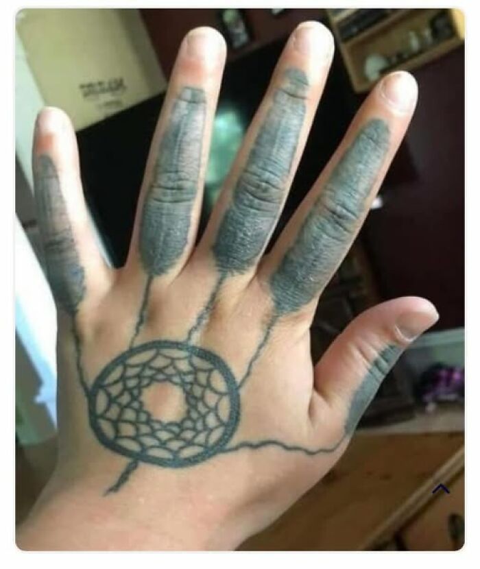 Hand with abysmally bad tattoos including poorly shaded fingers and a web-like design on the palm, showcasing some of the worst tattoos.