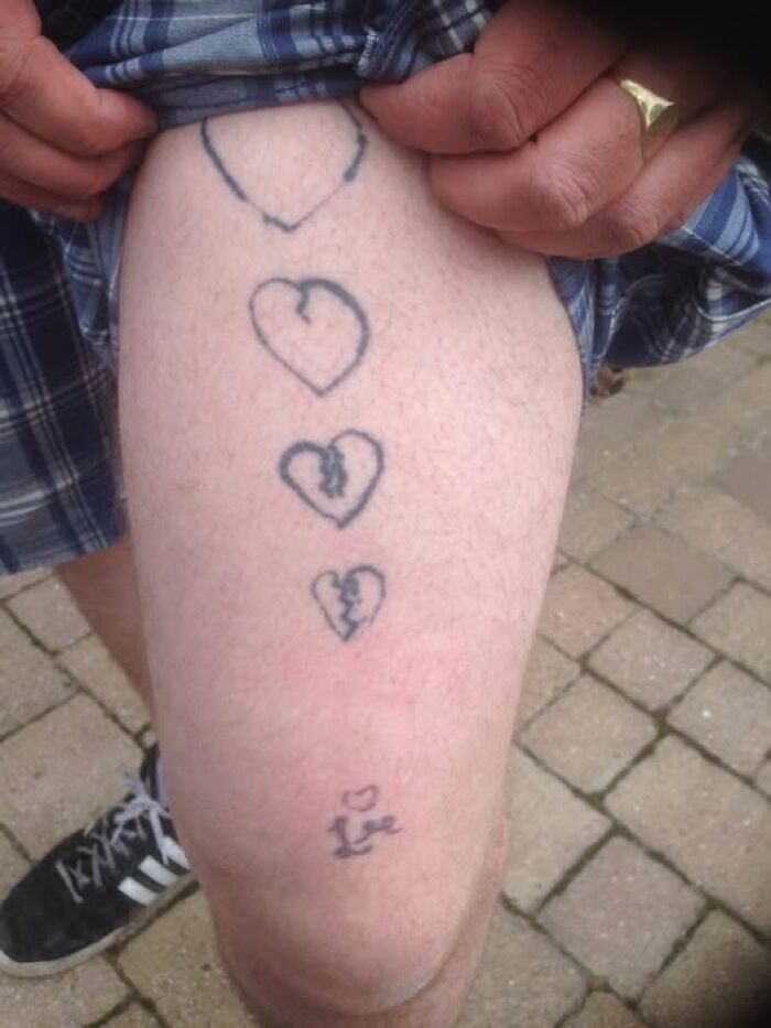 Tattoo of four broken hearts and a small love symbol on a person's leg, showcasing abysmally bad tattoos.