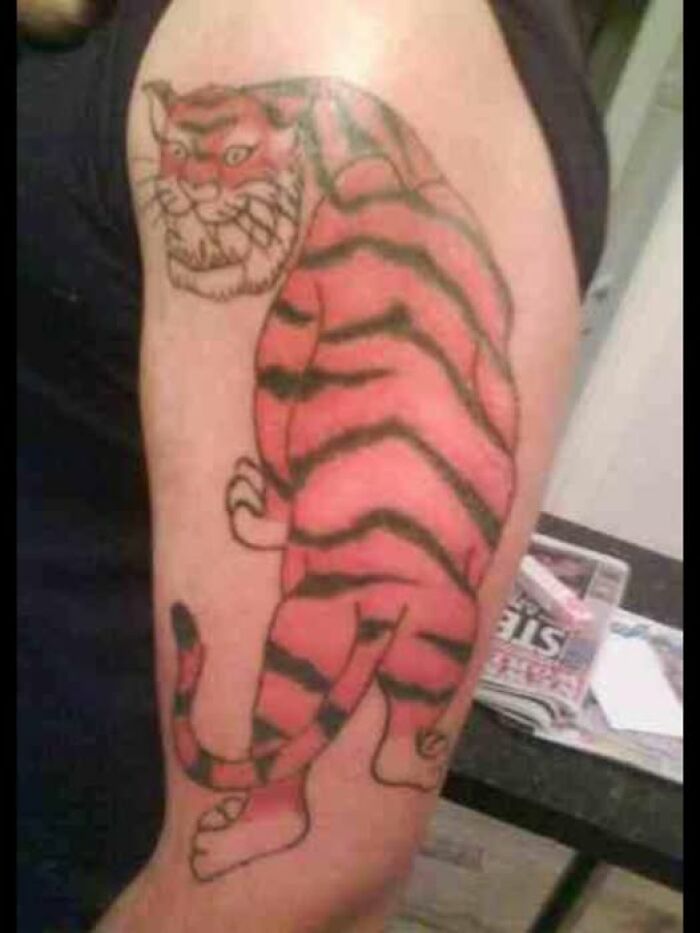 Tattoo of a poorly drawn tiger with uneven stripes on a person's upper arm, showcasing one of the worst bad tattoos.