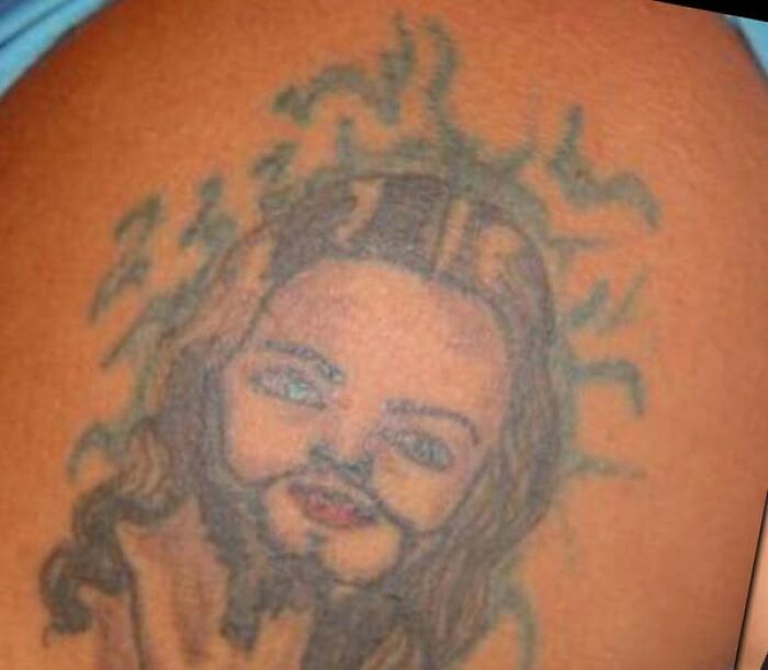 Tattoo of a bearded man with uneven features and blurred lines, an example of abysmally bad tattoos on skin.
