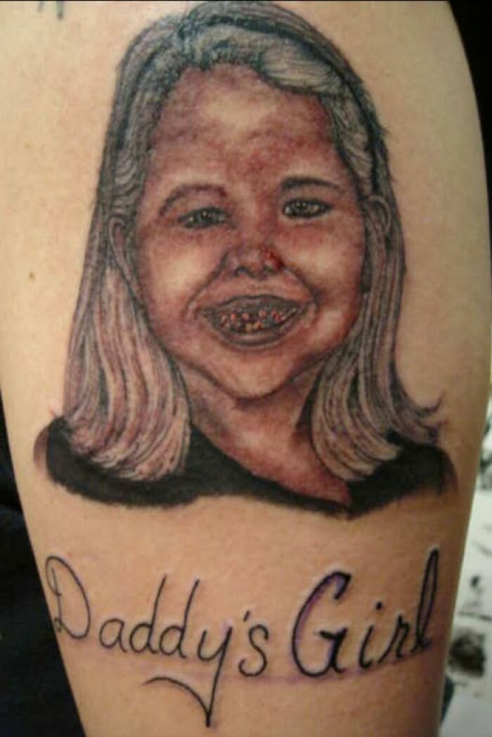 Tattoo of a distorted girl’s face with dated features and the text daddys girl, an example of abysmally bad tattoos.