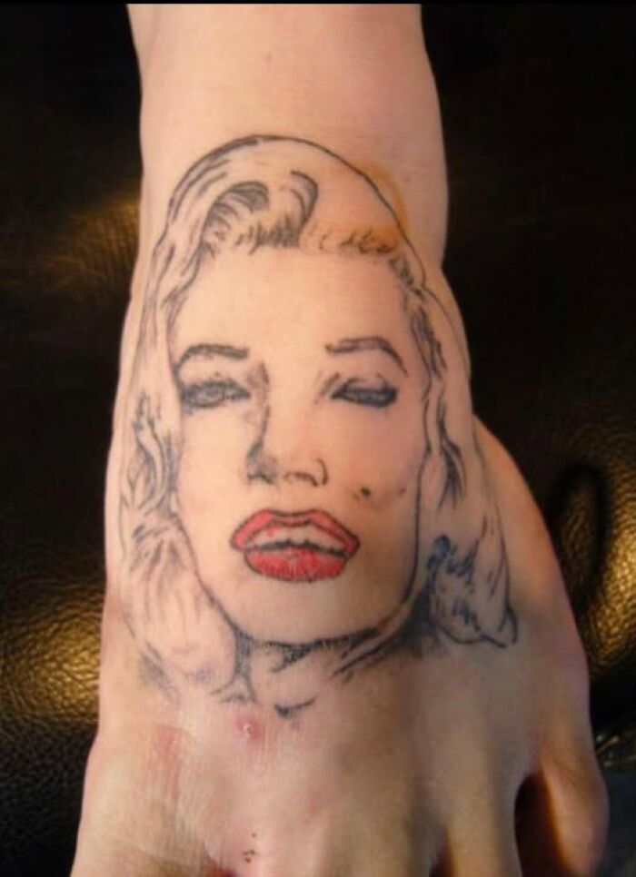 Tattoo of a poorly drawn female face on a foot, showcasing one of the worst abysmally bad tattoos on the skin.