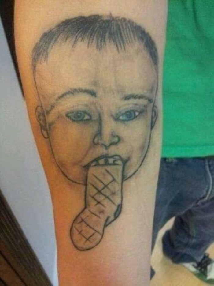 Tattoo of a baby with mismatched features and a distorted mouth, showcasing one of the worst bad tattoos examples.