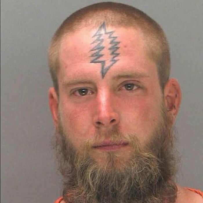 Man with an abysmally bad tattoo of a lightning bolt design on his forehead, part of worst tattoo collections.