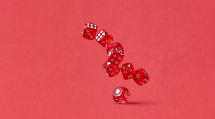Red dice mid-air against a red background, illustrating a concept related to a would you rather poll 2 game.