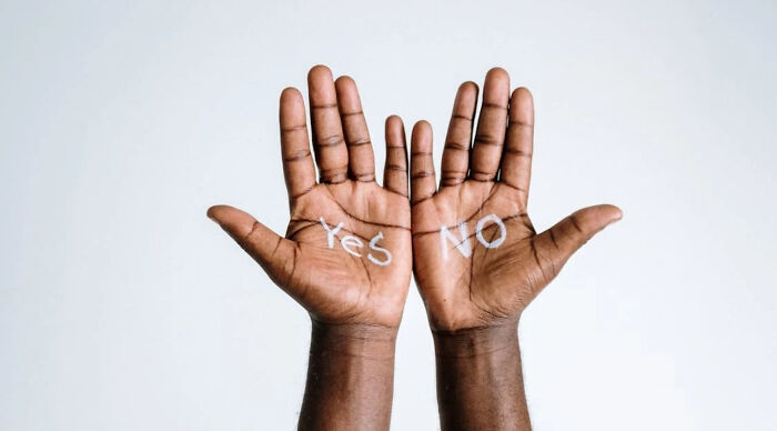 Pair of dark-skinned hands raised with yes and no written on palms representing a would you rather poll 2 concept.