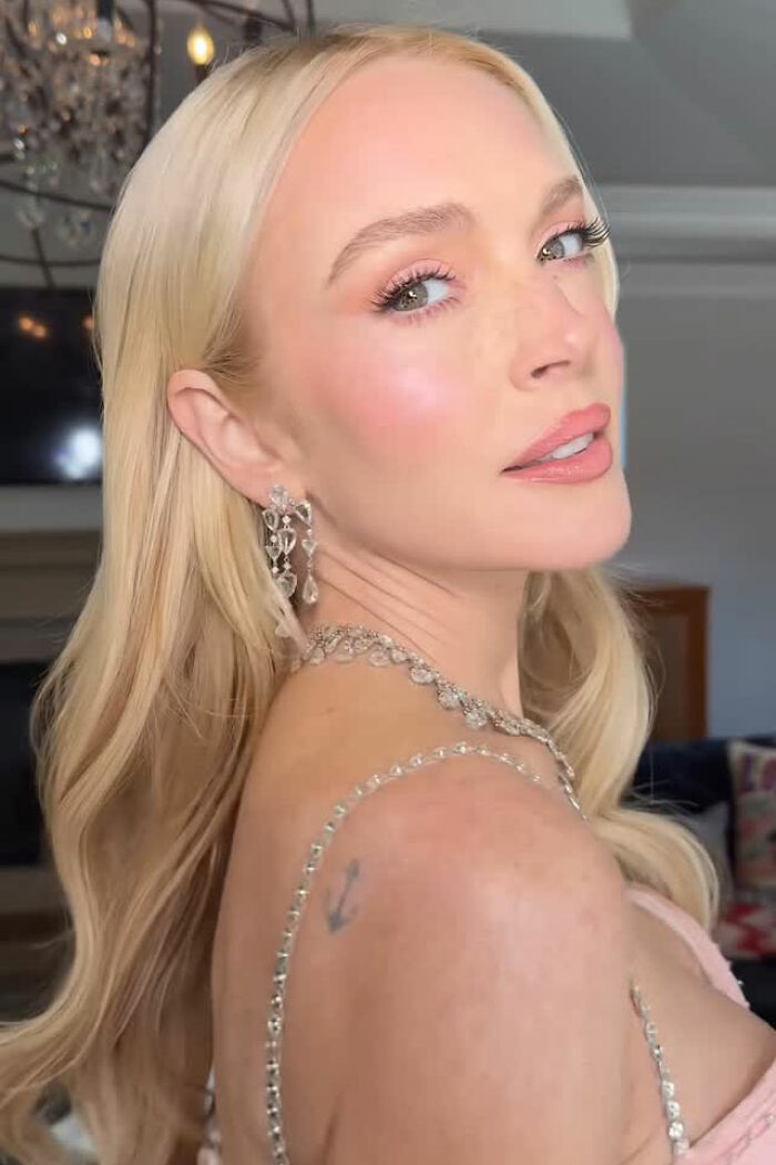 Lindsay Lohan with fresh-faced glow, wearing crystal earrings and necklace, highlighting youthful beauty amid plastic surgery debate.