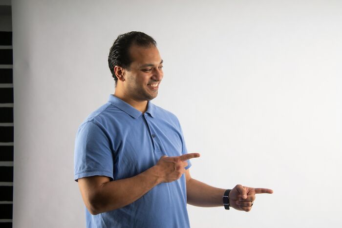 Man in a blue polo shirt smiling and pointing to the side illustrating bizarre beliefs people still fall for myth busted - 31