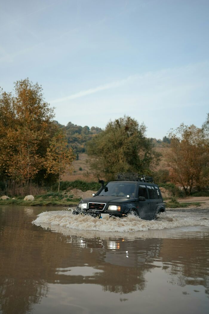 Off-road vehicle splashing through water in a rugged outdoor setting illustrating survival tips.