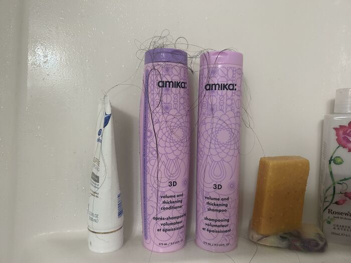 Shampoo and conditioner bottles in a shower with strands of hair on them, showing common roommate hygiene issues.