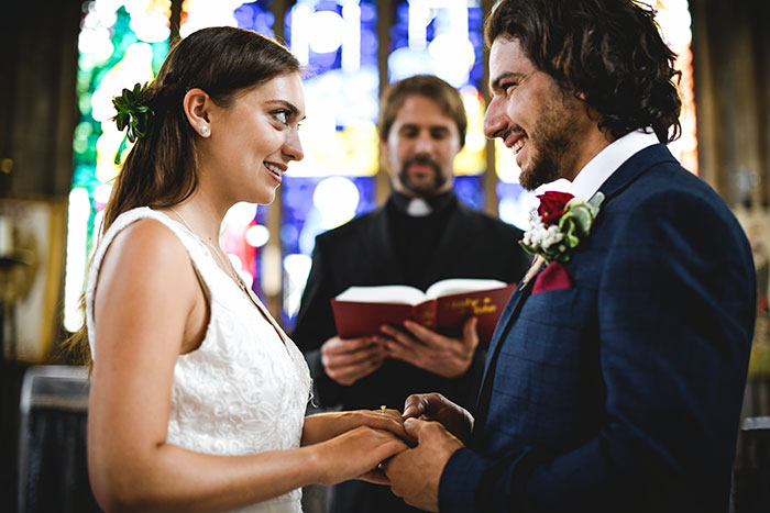 Bride and groom holding hands during wedding vows with a confused bride reacting in a church ceremony.