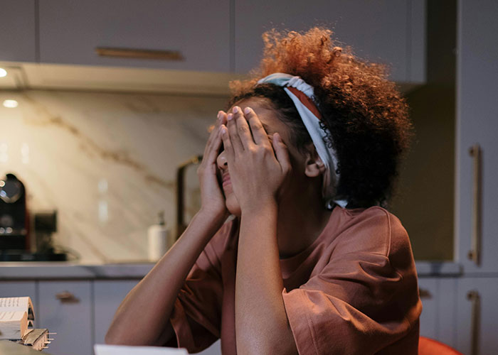 Woman looking stressed in kitchen, considering locking up food due to annoying cheap in-laws behavior.