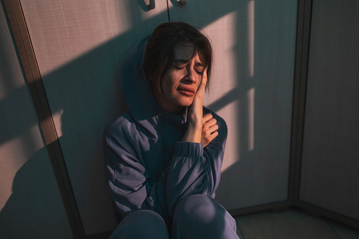 Claustrophobic woman sitting on the floor in tears, distressed and overwhelmed after a prank goes too far.