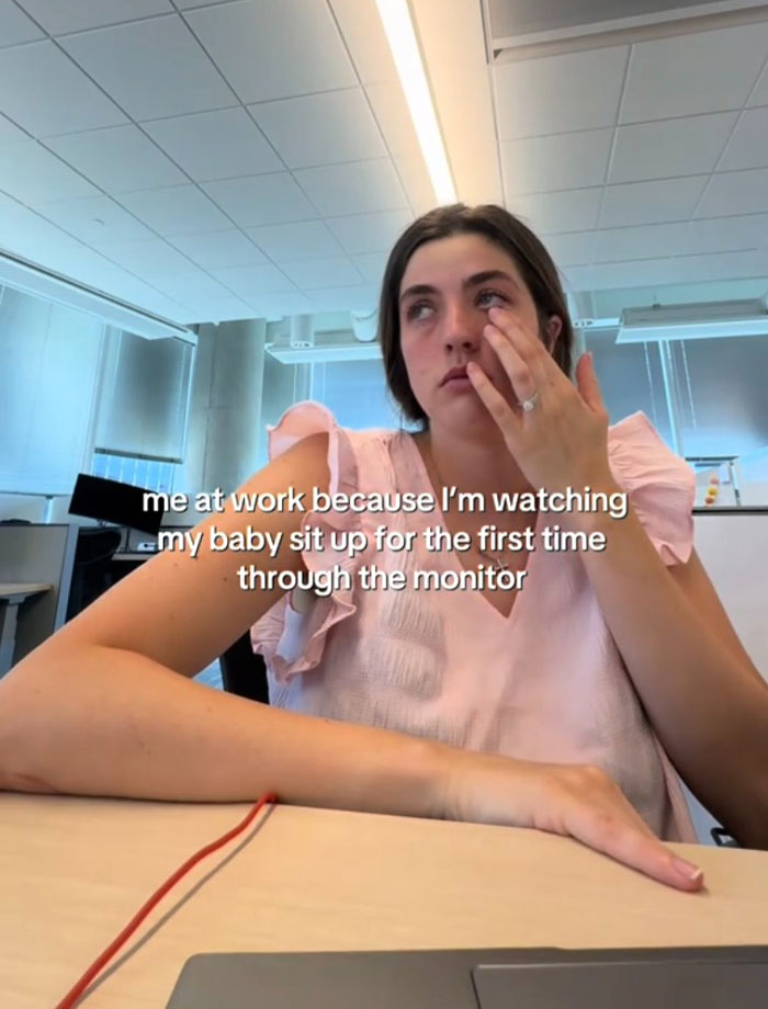 Tearful mom at work overwhelmed by missing moments of daughter growing up while watching through a monitor.