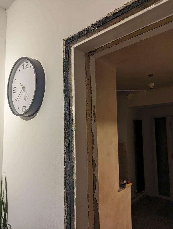 Partially renovated doorway with exposed wall edges and a clock on a white wall, showing weird home interior details. - 6