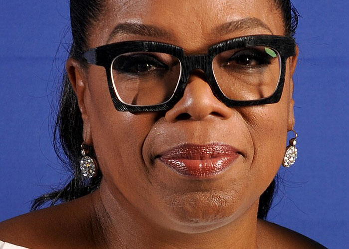 Close-up of a celebrity wearing large black glasses and earrings, representing wildest experiences running into celebrities.