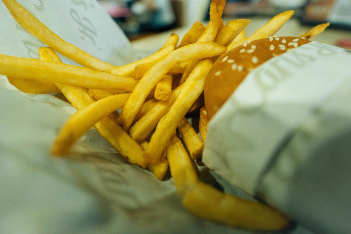 Close-up of French fries and a sesame seed burger wrapped in paper, illustrating unhinged wedding spends food choices. - 6