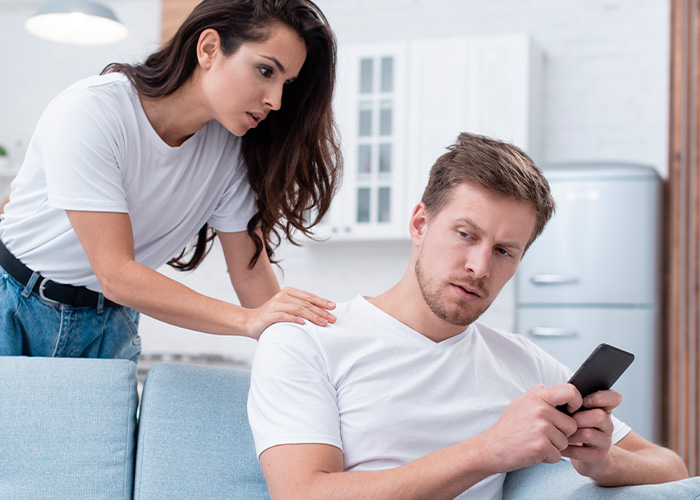 Young woman confronting man holding phone, capturing a moment of tension and regret from ignoring gut feeling.