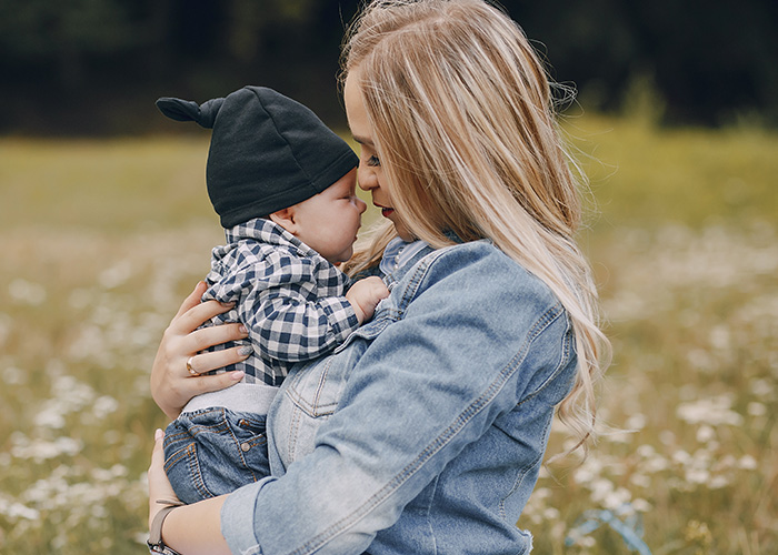 Mother holding baby outside in a field, capturing the feeling of being lucky to be alive and cherishing the moment.