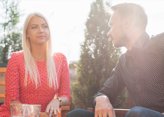A man and woman sitting outdoors having a serious conversation, illustrating gut feeling and regret moments.