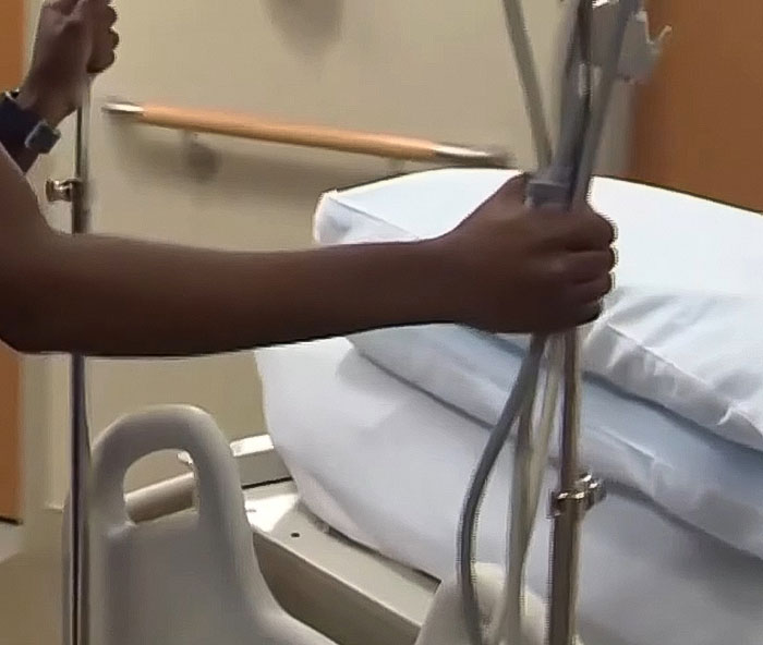 Nurse adjusting hospital bed and IV pole in patient room related to hospital fires 15 nurses after patient incident.