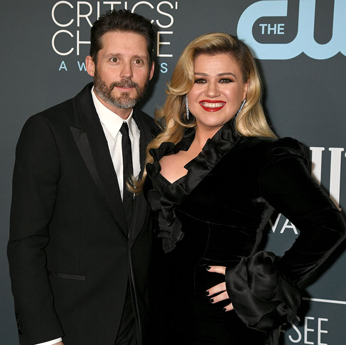 Brandon Blackstock and Kelly Clarkson posing together on the red carpet at a Critics' Choice Awards event.