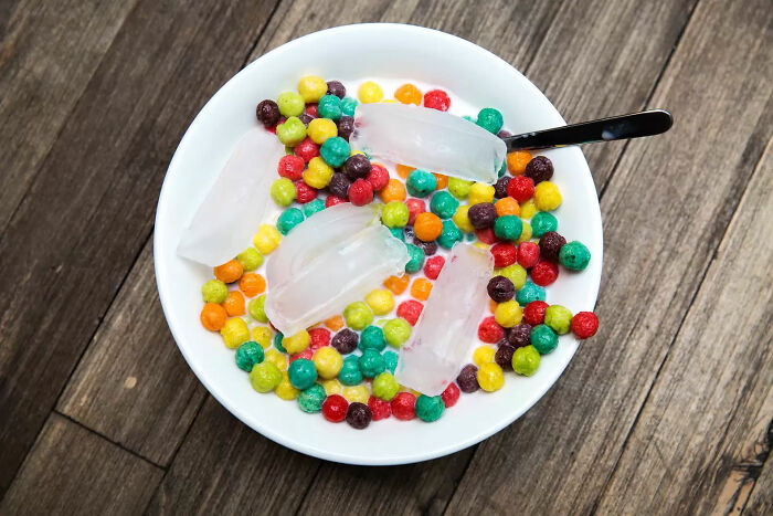 Bowl of colorful candy with ice cubes and a spoon, representing food nobody should eat for mental health.