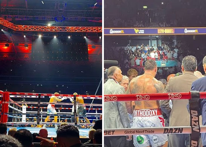 Boxing match in progress with crowd watching closely and a fighter with Orthodox shorts standing near the ring ropes